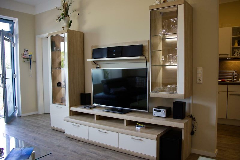TV und Regale im Wohnzimmer der Ferienwohnung am Südstrand, in der Strandburg