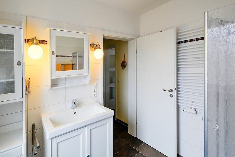 Badezimmer mit Waschbecken und Handtuchheizung in der Ferienwohnung auf Fehmarn