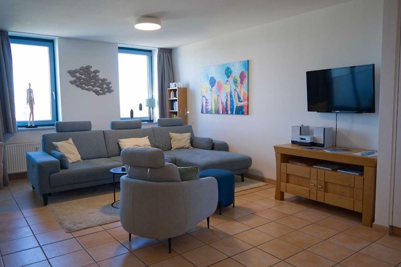 Wohnzimmer mit Couch und Sessel in der Ferienwohnung in der Strandburg auf Fehmarn