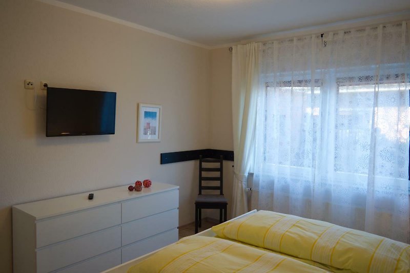 Kommode und TV am Fussende des Doppelbetts in der Ferienwohnung in Landkirchen