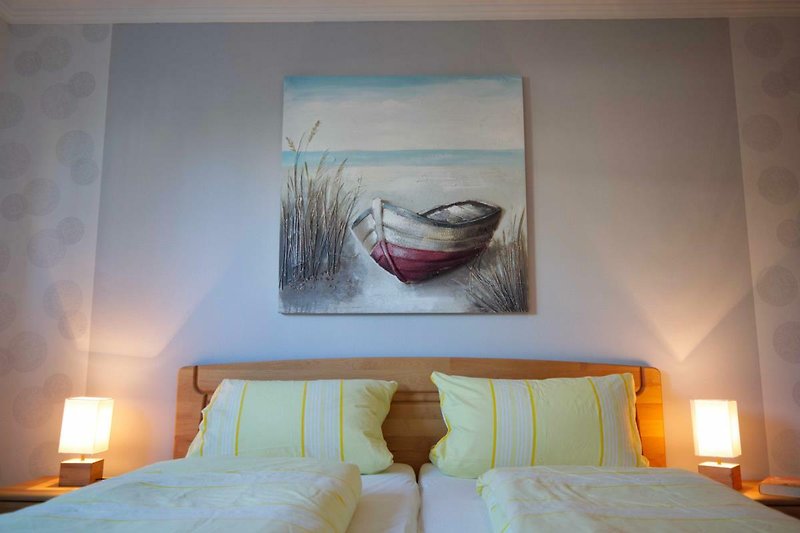 Doppelbett mit Bild vom Schiff in der Ferienwohnung Inselblume 15 mit Garten