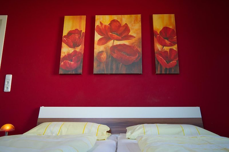 Doppelbett mit Bildern von Mohn über dem Bett in dem Ferienhaus auf Fehmarn