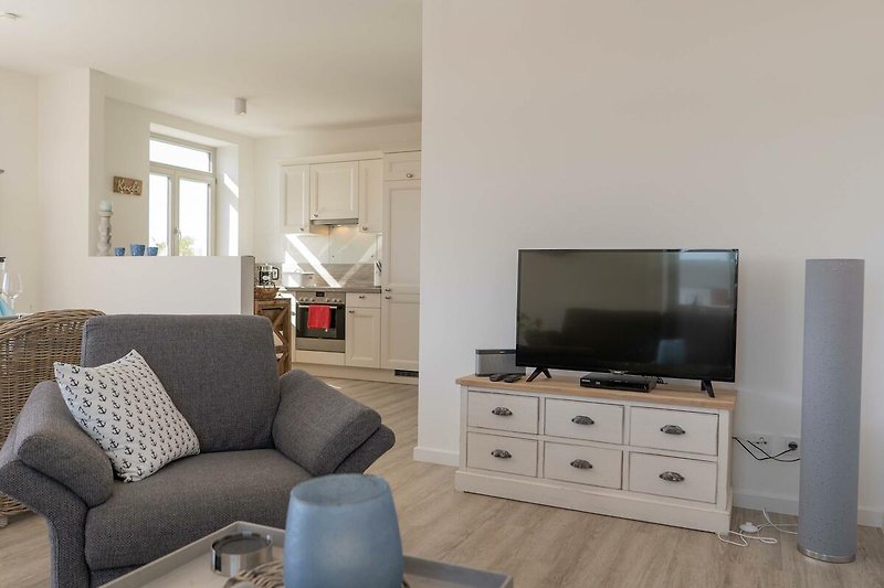 TV und Sessel mit Blick Richtung Küche in der Ferienwohnung auf Fehmarn