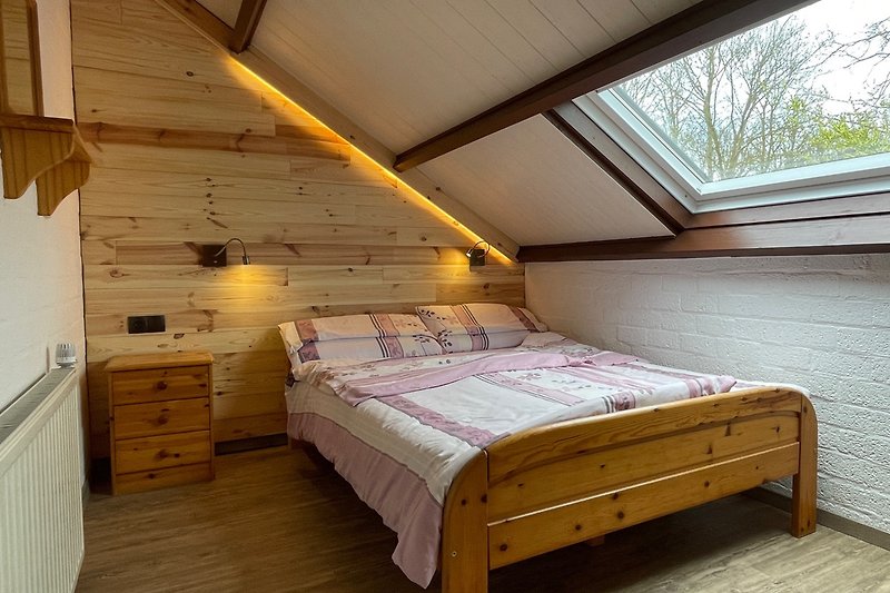 Schlafzimmer im Dachgeschoß mit Holzverkleidung und gemütlichem Bett.