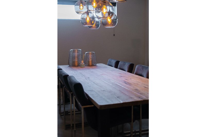 Gemütliche Einrichtung mit Holztisch, Stühlen und stilvoller Beleuchtung.