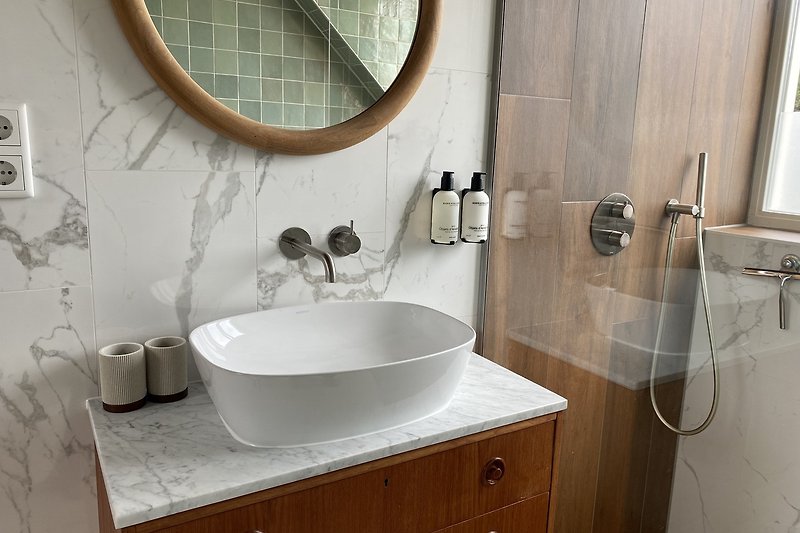 Een moderne badkamer met een spiegel, kraan en wastafel.