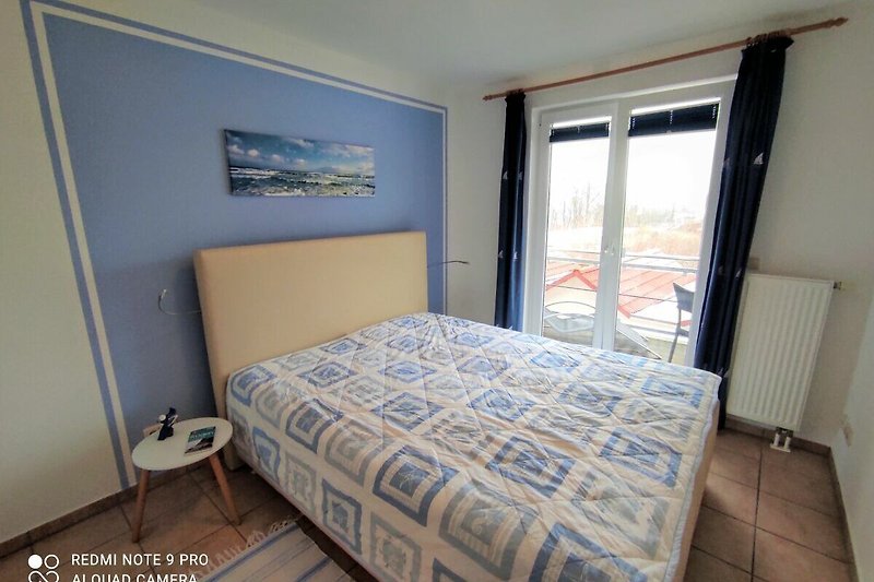 Gemütliches Schlafzimmer mit bequemem Bett und Zugang zu einem der beiden Balkone