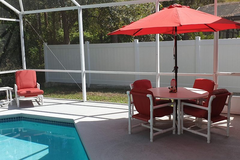 Pool mit Sonnenschirmen, Stühlen und Tischen.
