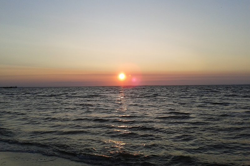 Eine ruhige Küste mit einem atemberaubenden Sonnenuntergang über dem Wasser.