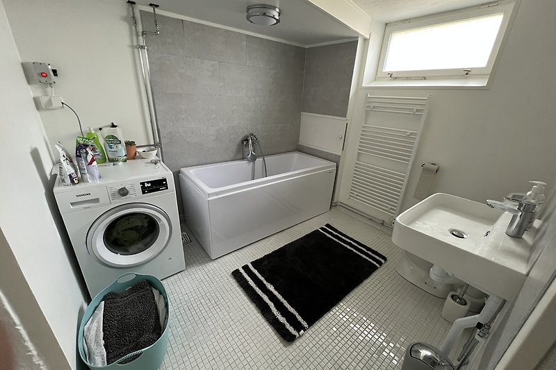 Large bathroom in the basement with bathtub & washing machine