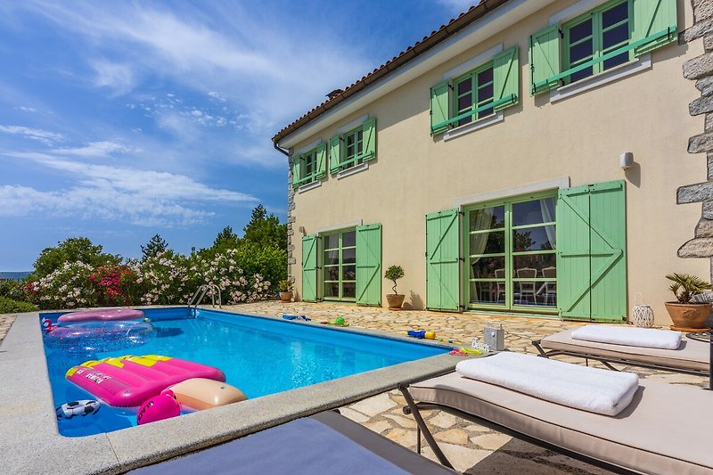 A stunning property with a swimming pool, outdoor furniture, and beautiful landscape.