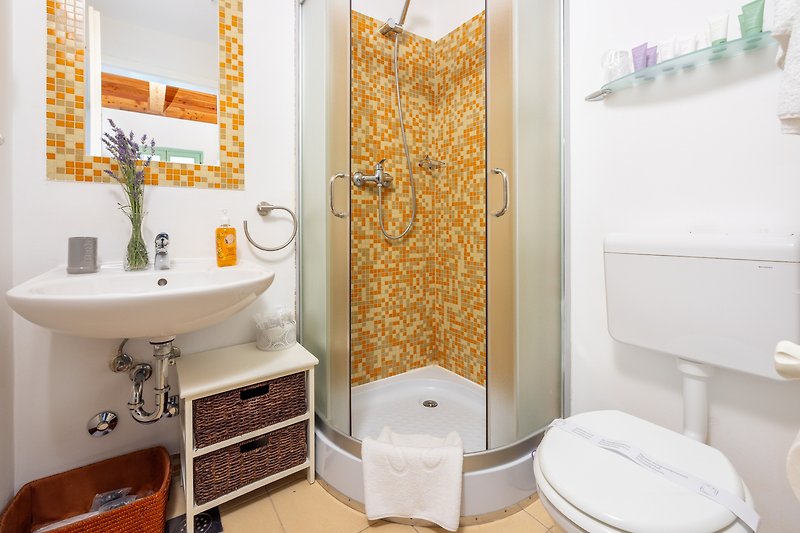 Badezimmer mit weißem Waschbecken, lila Vorhang und Holztür.
