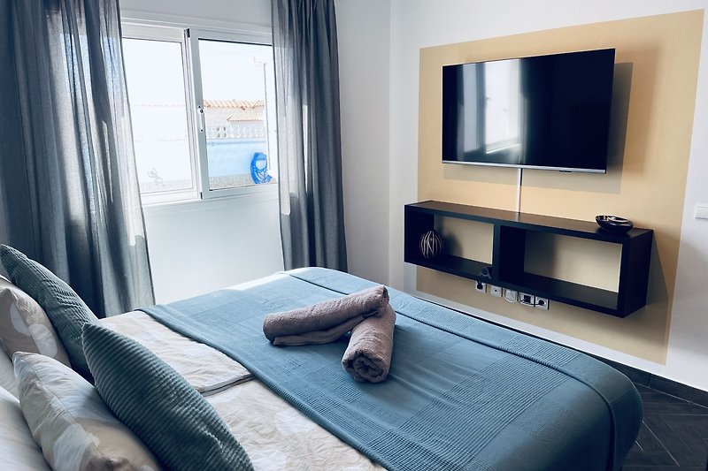 Schlafzimmer mit Doppelbett und Fernseher