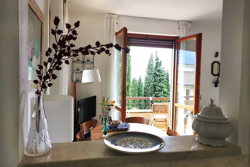 Großzügige Küche mit Durchreiche ins Wohnzimmer und Ausblick mit Zypressen und Teile des Gardasees
