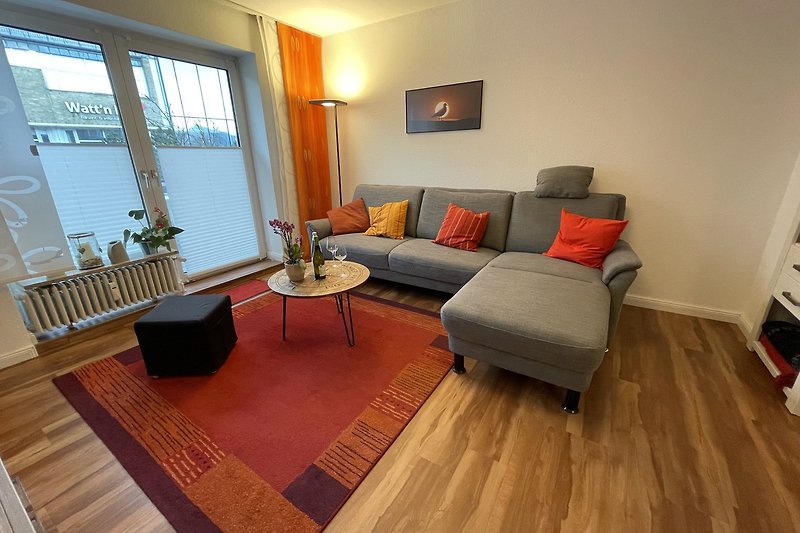 Wohnzimmer mit Holzmöbeln, Tisch, Sofa, Lampe und Pflanze.