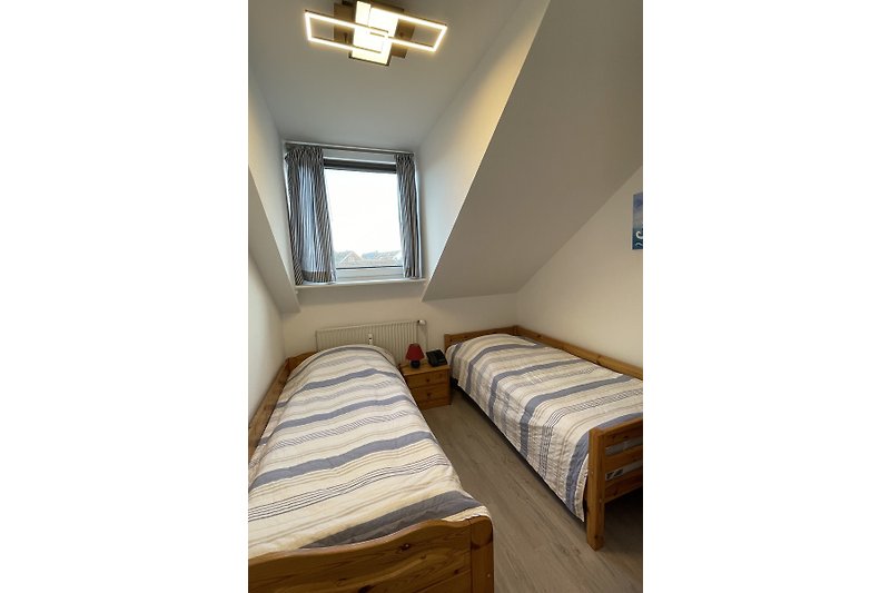Schlafzimmer mit Holzfenster, Vorhang, Bett und Lampe.