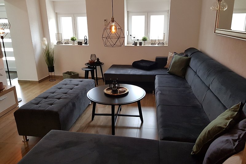 Gemütliches Wohnzimmer mit bequemer Couch, Holzmöbeln und stilvollem Design.
