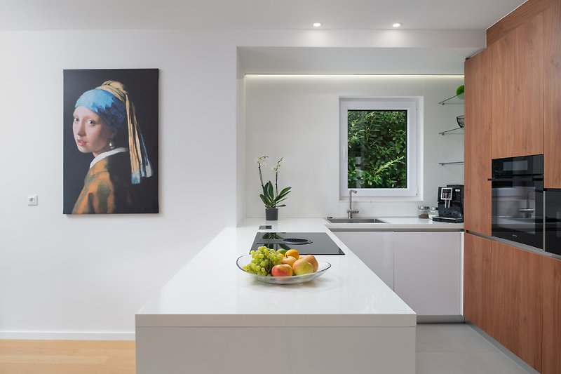 Schöne Küche mit weißer Schrankwand, Arbeitsplatte und Holzboden.