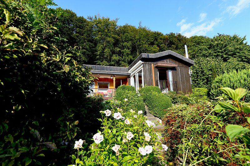 Schönes Ferienhaus mit blühenden Pflanzen, grünem Garten und malerischer Landschaft.