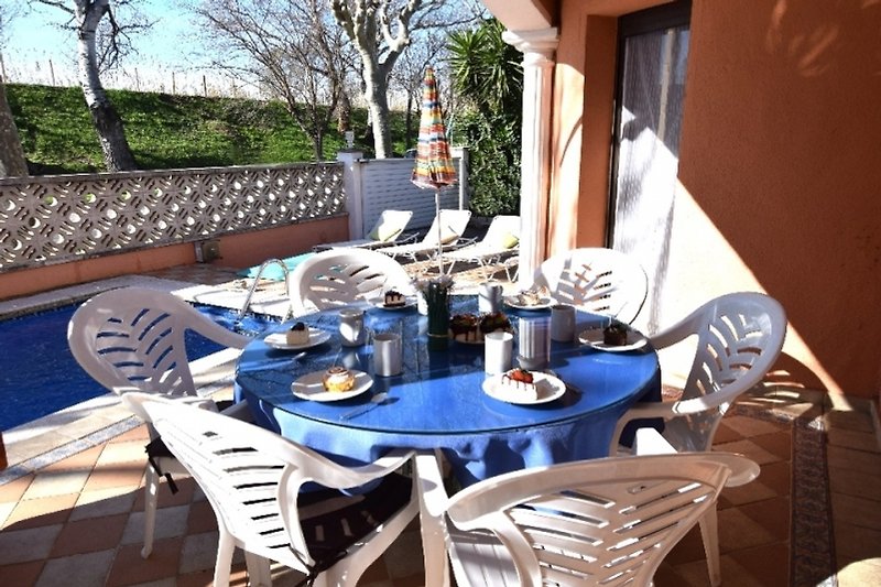 Gemütliche Terrasse mit Tisch, Stühlen und Blumen.