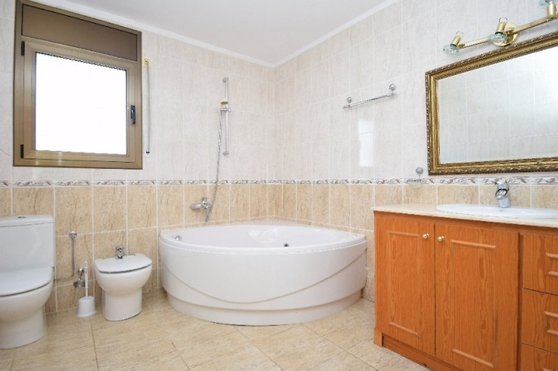 Badezimmer mit lila Badewanne, Holzboden und Fenster.