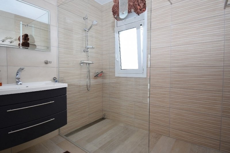 Schönes Badezimmer mit Spiegel, Waschtisch und Holzboden.