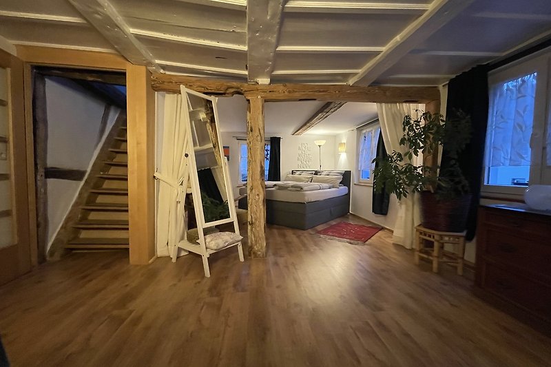 Maison de ville élégante avec plafond en bois, escalier, plantes et mobilier moderne.