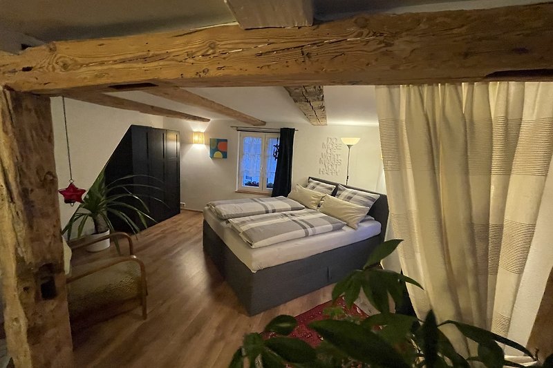 Espace de couchage rustique et confortable au premier étage avec un lit double et une armoire.
