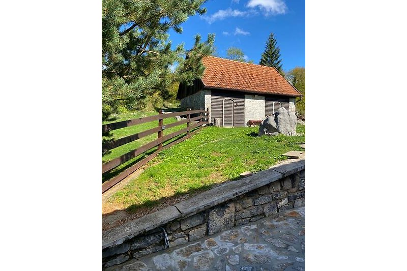 A charming cottage nestled in a picturesque landscape with a split-rail fence and lush greenery.