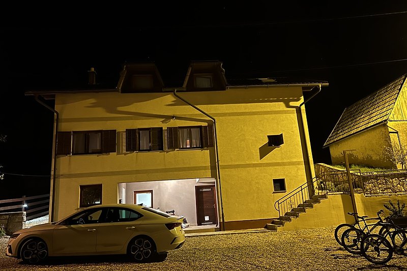 A yellow car parked in front of a building at night.