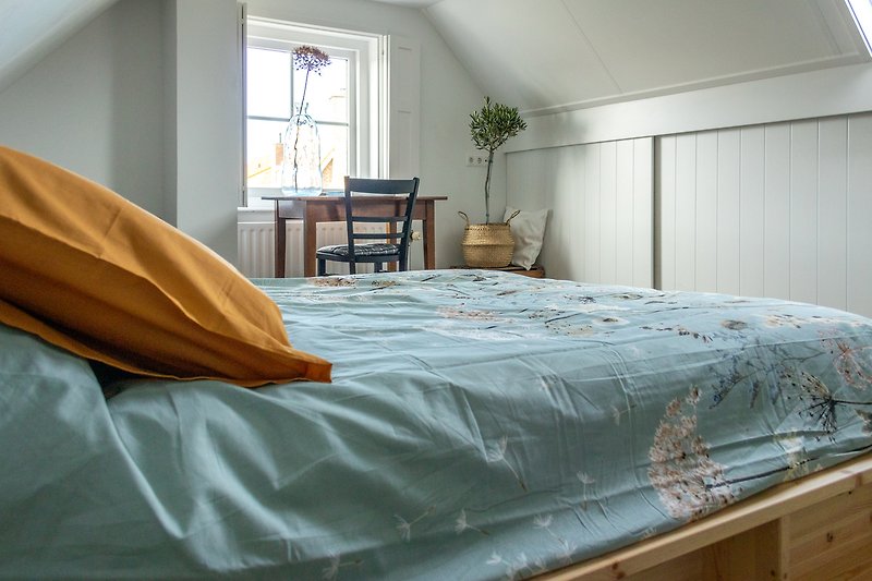 Een ruime slaapkamer met een comfortable matras.