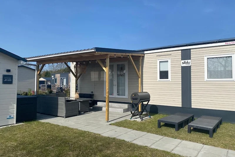 Mobilheim mit markanter Verkleidung und eigenem Caravan direkt am Platz.