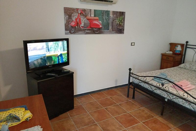 Appartamento con arredamento moderno, TV a schermo piatto e pareti in legno. Il comfort è garantito.