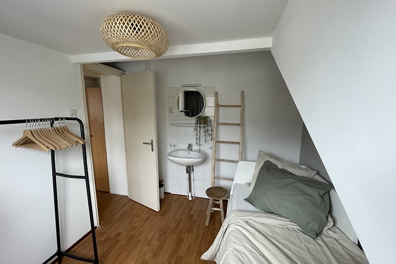 Comfortabele slaapkamer met houten vloer, bed en lamp.