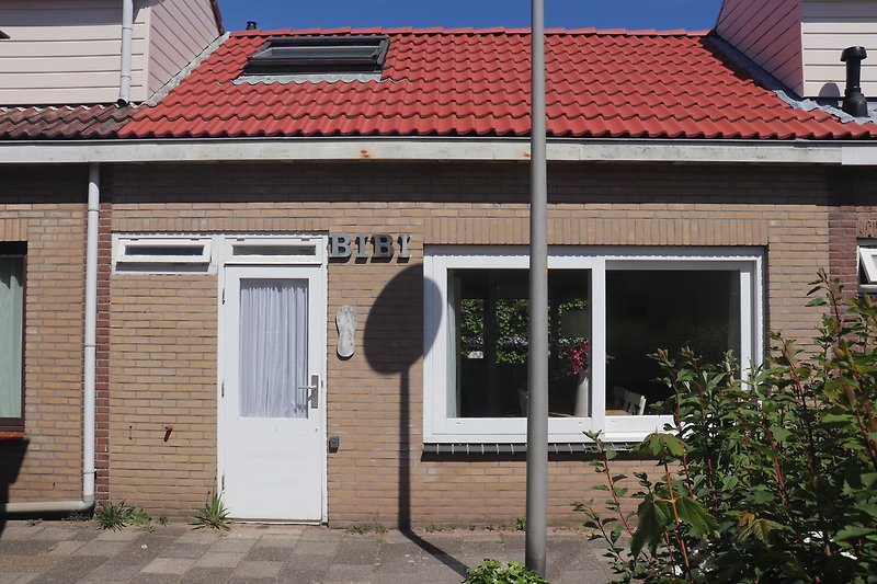 Charmantes Backsteinhaus mit Holzfenster und Pflanzen im Vorort.