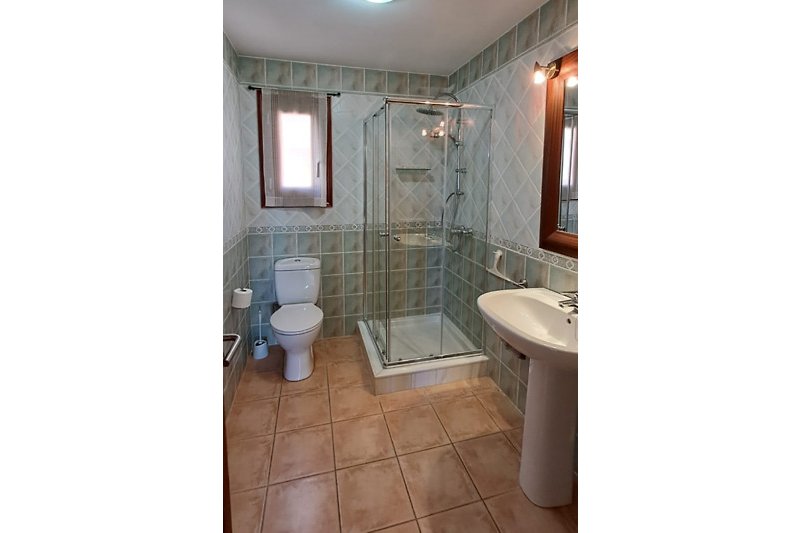 Modernes Badezimmer mit Glaswand, Keramikwaschbecken und Dusche.