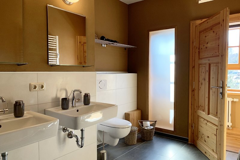 Großes Bad mit ebenerdiger Dusche,Doppelwaschbecken und WC. Ein weiteres WC steht auf halber Treppe zur Verfügung