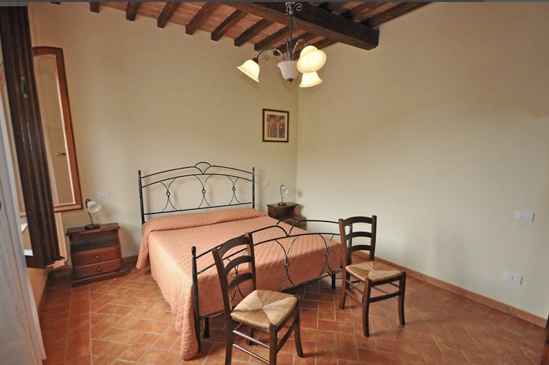 Un'incantevole camera da letto con mobili in legno e un elegante design d'interni in stile rustico toscano.(trilo 7)