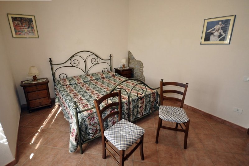 Camera  matrimoniale con design in stile rustico toscano con letto in ferro battuto