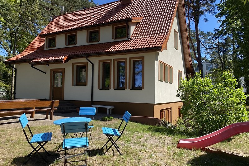 Holzhaus mit Veranda und großem Garten im Schatten.