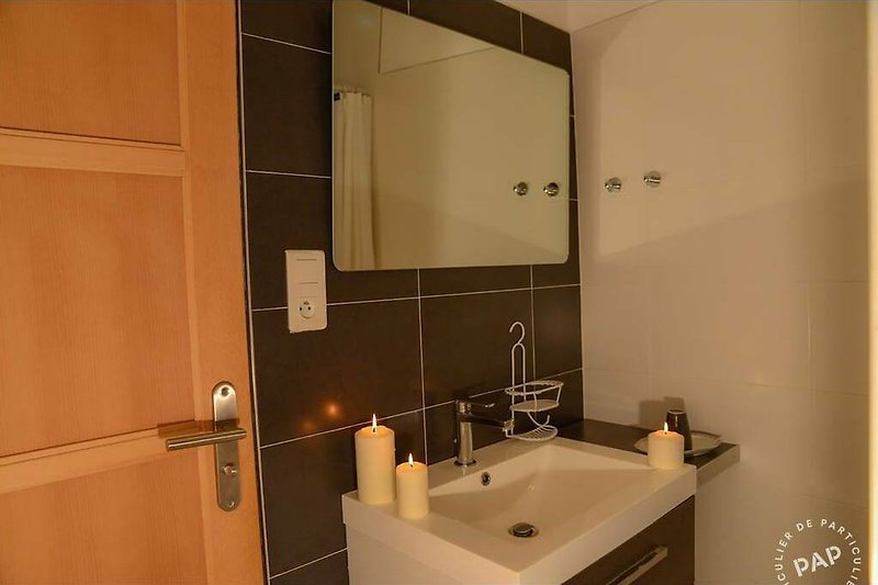 Détendez-vous dans cette salle de bain moderne avec un miroir, un lavabo et des armoires en bois.