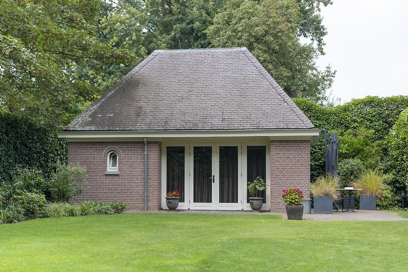 Historisches Bauernhaus mit blühenden Blumen und gepflegtem Rasen.