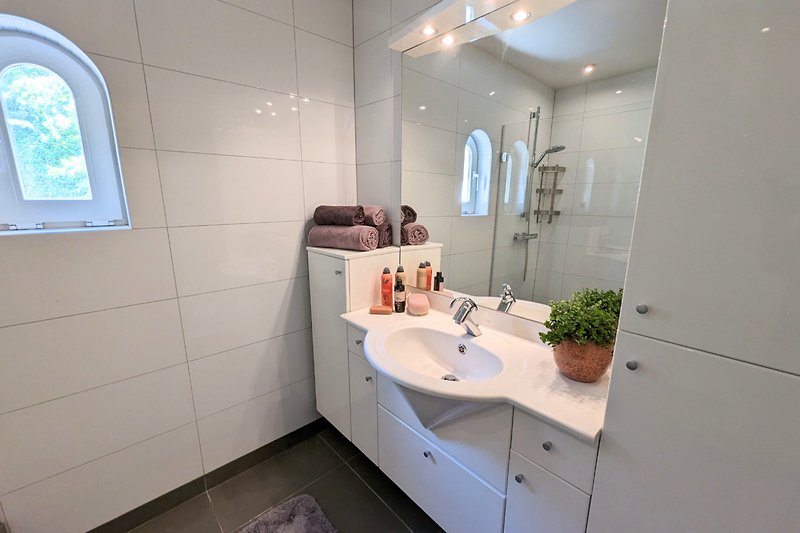 Ein geräumiges Badezimmer mit Haartrockner und bereits vorhandenen Handtüchern.