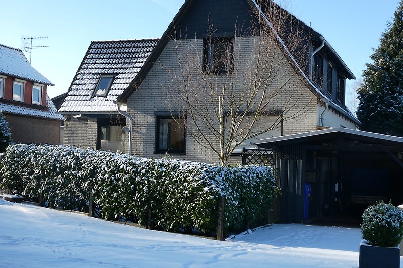 Gemütliches Winterhaus mit verschneitem Dach und malerischer Landschaft.