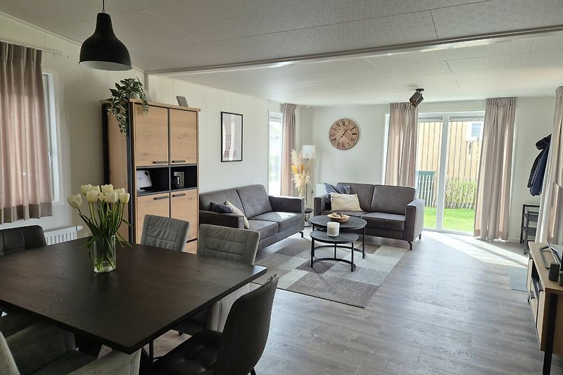 Wohnzimmer mit Tisch, Stühlen, Sofa, Pflanze und Lampe.
