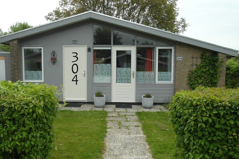 Gemütlicher Garten mit Rasen, Bäumen und Gartenhaus.