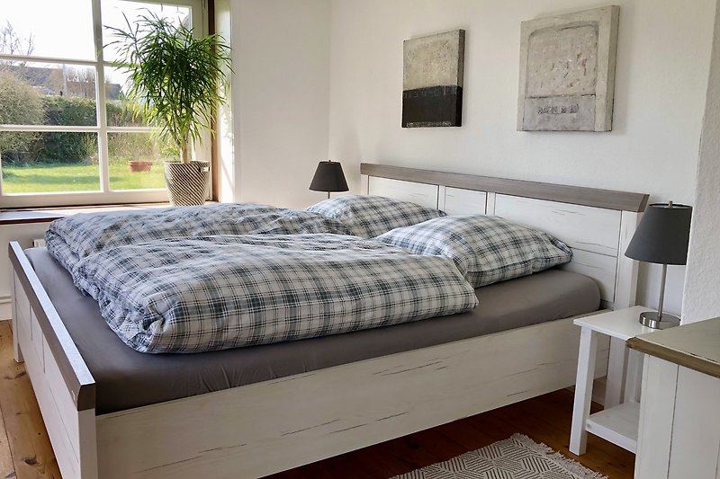 Gemütliches Schlafzimmer mit Holzbett, bequemem Bett und stilvollem Interieur.