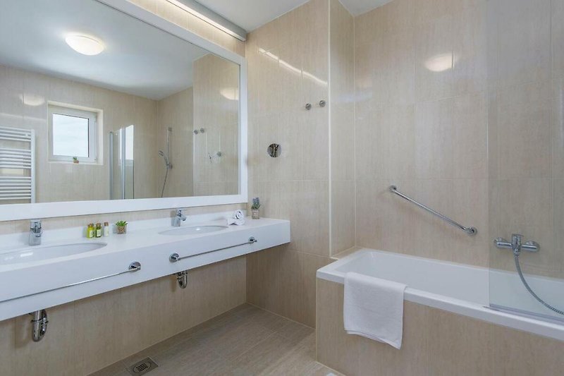 Schönes Badezimmer mit Spiegel, Waschbecken, Badewanne und Armatur.