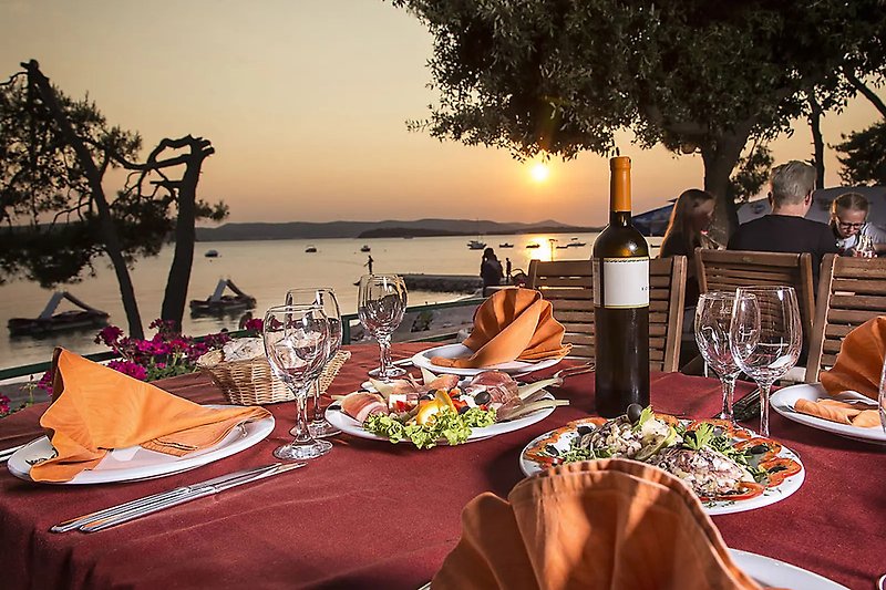 Enjoy a sunset dinner by the lake with delicious food and a glass of wine.