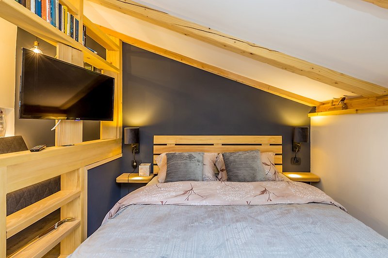 Udobna spavaća soba s drvenim namještajem i svijetlim osvjetljenjem.
